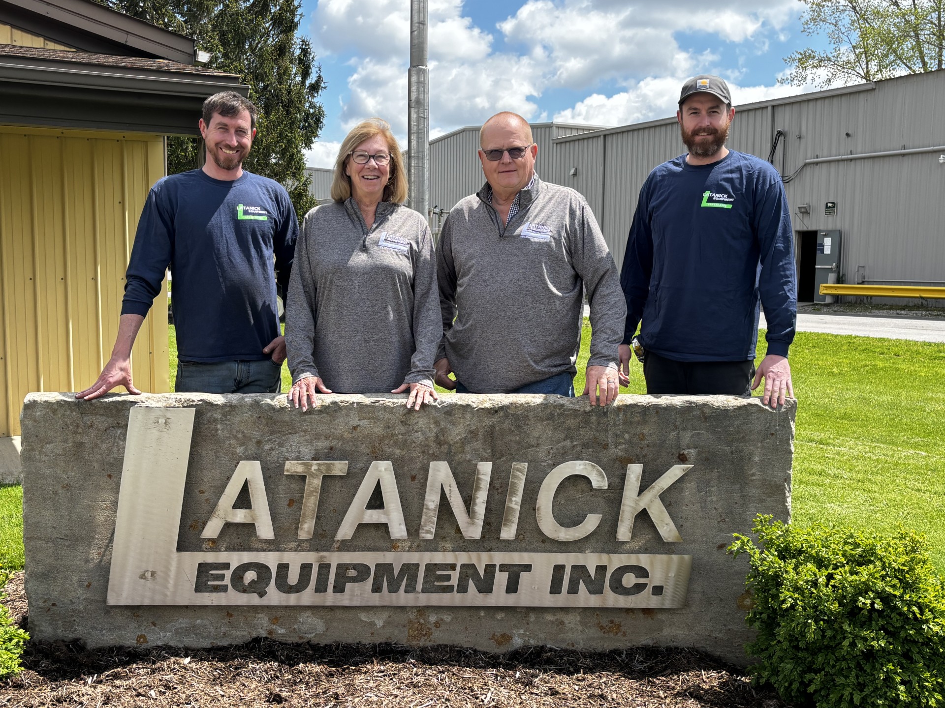 Ryan, Judy, Rick, and Brandon Poorman in front of the Latanick Equipment Inc. sign